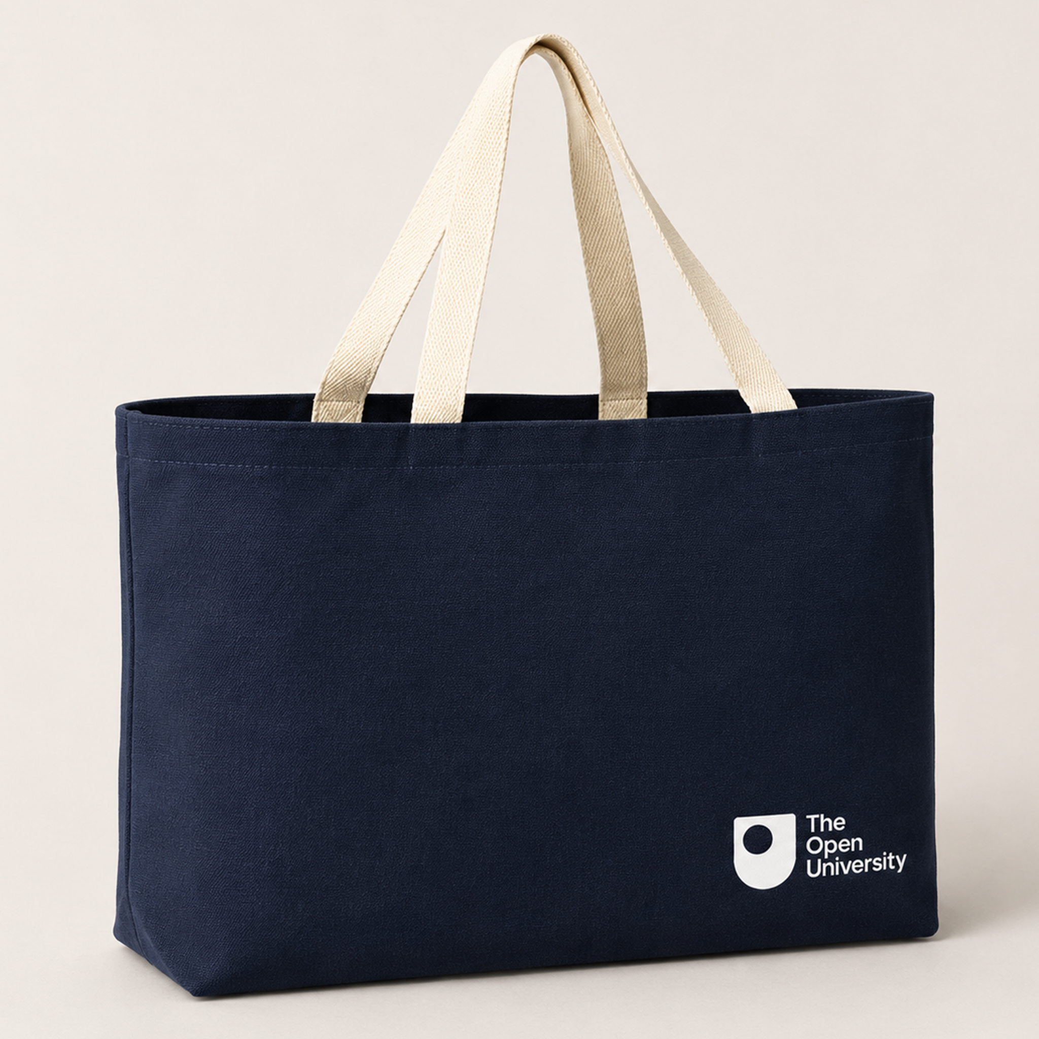 Navy canvas tote bag with cream webbing handles and a white The Open University logo in the bottom right corner