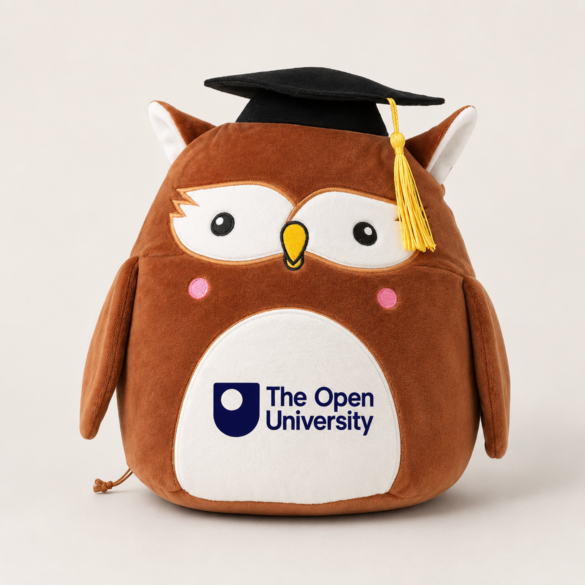 Brown squidgy plush owl with embroidered facial features, pink cheek accents, and a black graduation cap with yellow tassel. The white Open University logo is printed on its chest