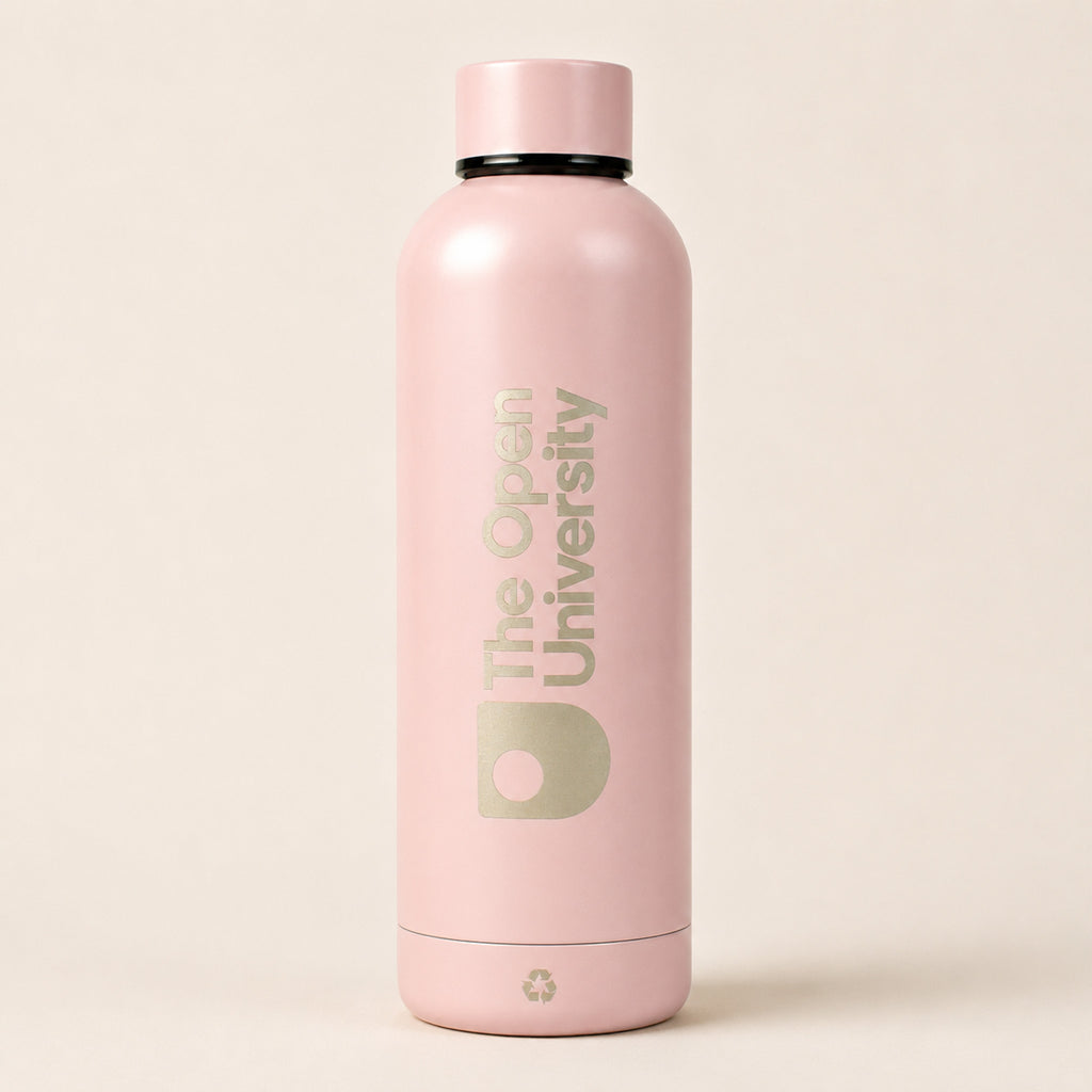 A matte light pink insulated water bottle with a matching pink cap, featuring 'The Open University' printed vertically in a muted sage green on the front, set against a solid light beige background.